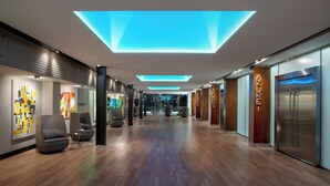 A modern hotel lobby with wooden flooring, contemporary chairs, and illuminated ceiling panels. - The Westin Houston Medical Center/Museum District (Houston)