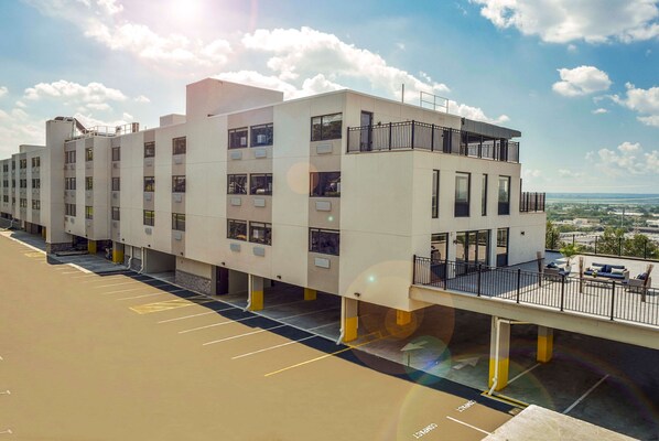 Un edificio moderno de varios pisos con una terraza en la azotea y un paseo techado.