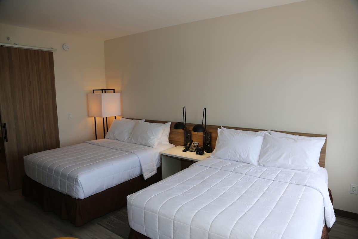 Ein Hotelzimmer mit zwei Einzelbetten, einem Holzkopfende, Nachttischlampen und einem Telefon.