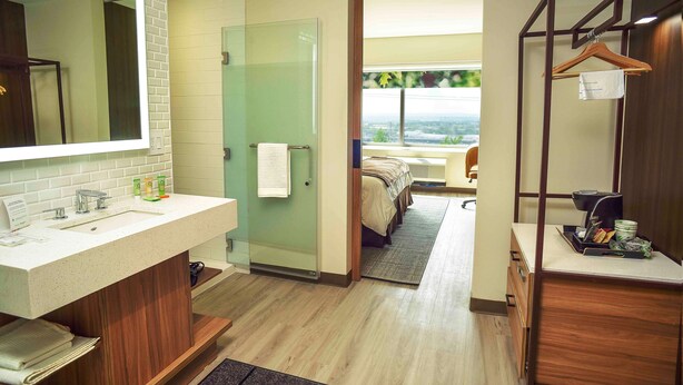 A modern hotel bathroom with a large mirror, a sink, and a shower area. - Wyndham Garden North Bergen Near Secaucus (North Bergen)