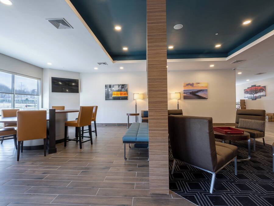 Un vestíbulo de hotel moderno con zona de comedor, arreglos de asientos y obras de arte en las paredes.