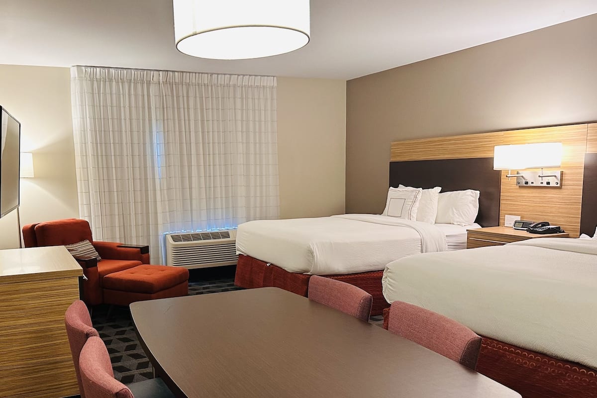 A hotel room with a bed, a desk, a chair, and a table.