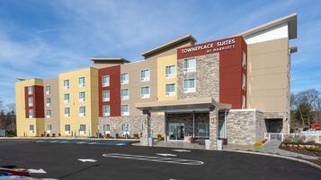 A multi-story hotel with a modern design, featuring a prominent entrance with a glass door and a sign that reads "TOWNEPLACE SUITES BY MARRIOTT."