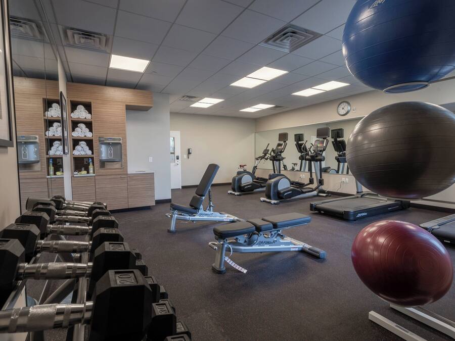 A gym with exercise equipment, a mirror, and a clock on the wall.