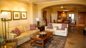 Una sala de estar con un sofá, sillones, una mesa de centro y un comedor al fondo.
