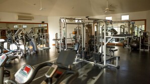 Un gimnasio con varios equipos de ejercicio, incluyendo cintas de correr, máquinas de pesas y pesas libres.
