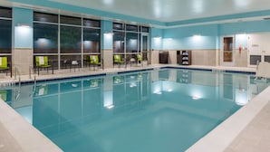 An indoor swimming pool with clear water, a tiled floor, and several chairs along the poolside. - SpringHill Suites by Marriott Suwanee Johns Creek (Suwanee)