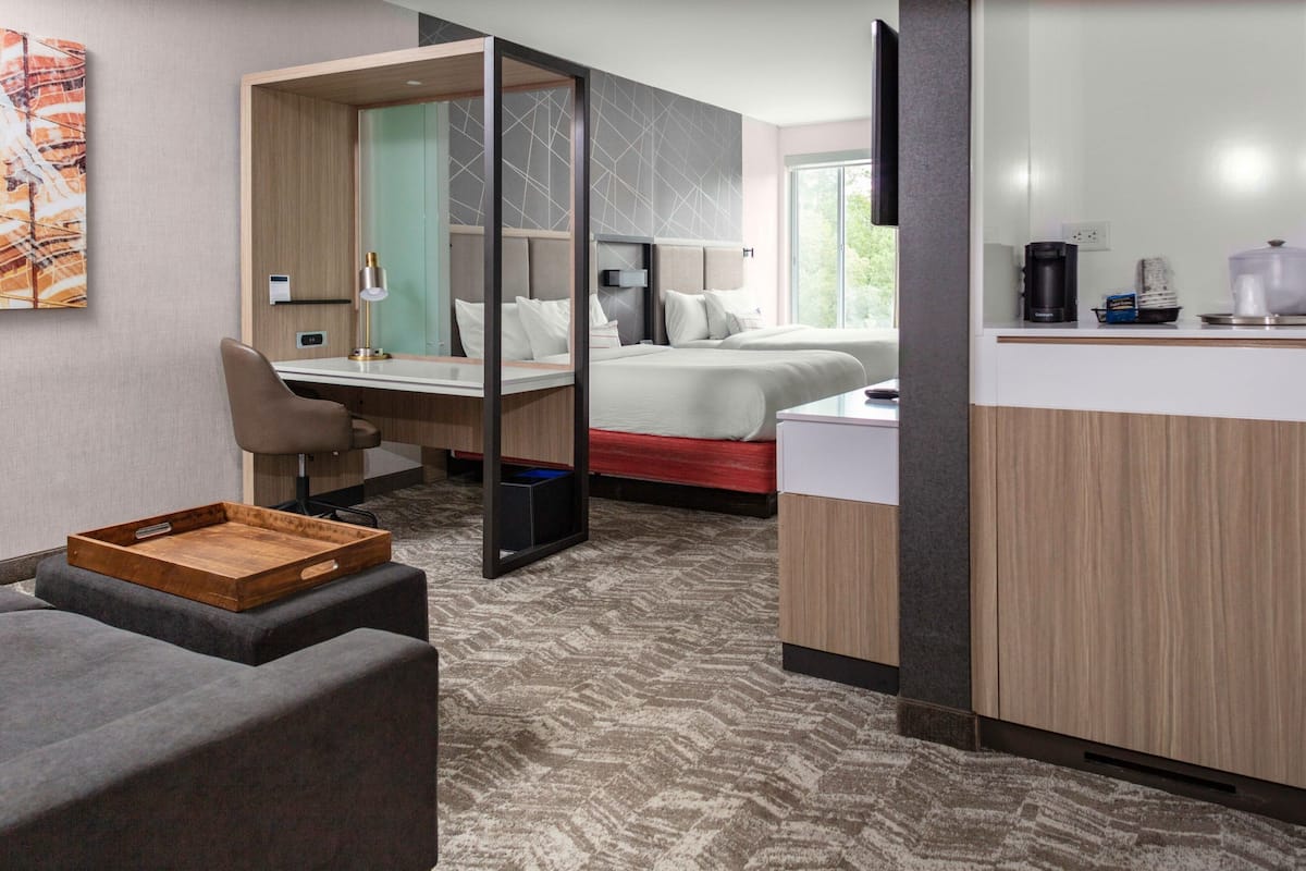 Una habitación de hotel moderna con cama, escritorio, silla y kitchenette.