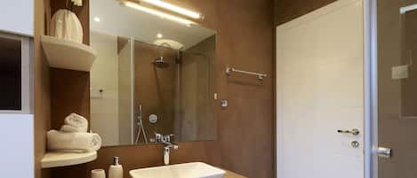 Un baño moderno con un espejo grande, un lavamanos blanco y una ducha.