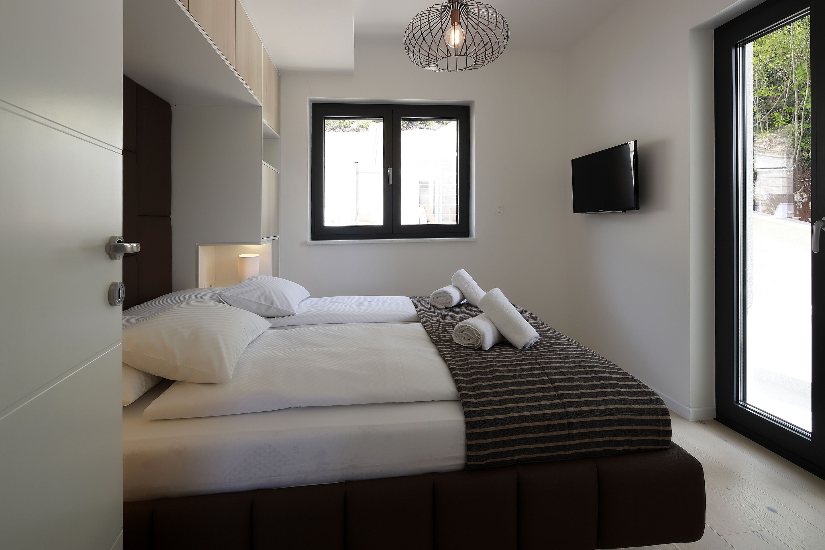Ein modernes Schlafzimmer mit einem Bett, einem Fernseher und einem großen Fenster.