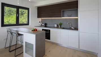 Una cocina moderna con un ventanal grande, taburetes de bar, horno empotrado y un lavamanos.