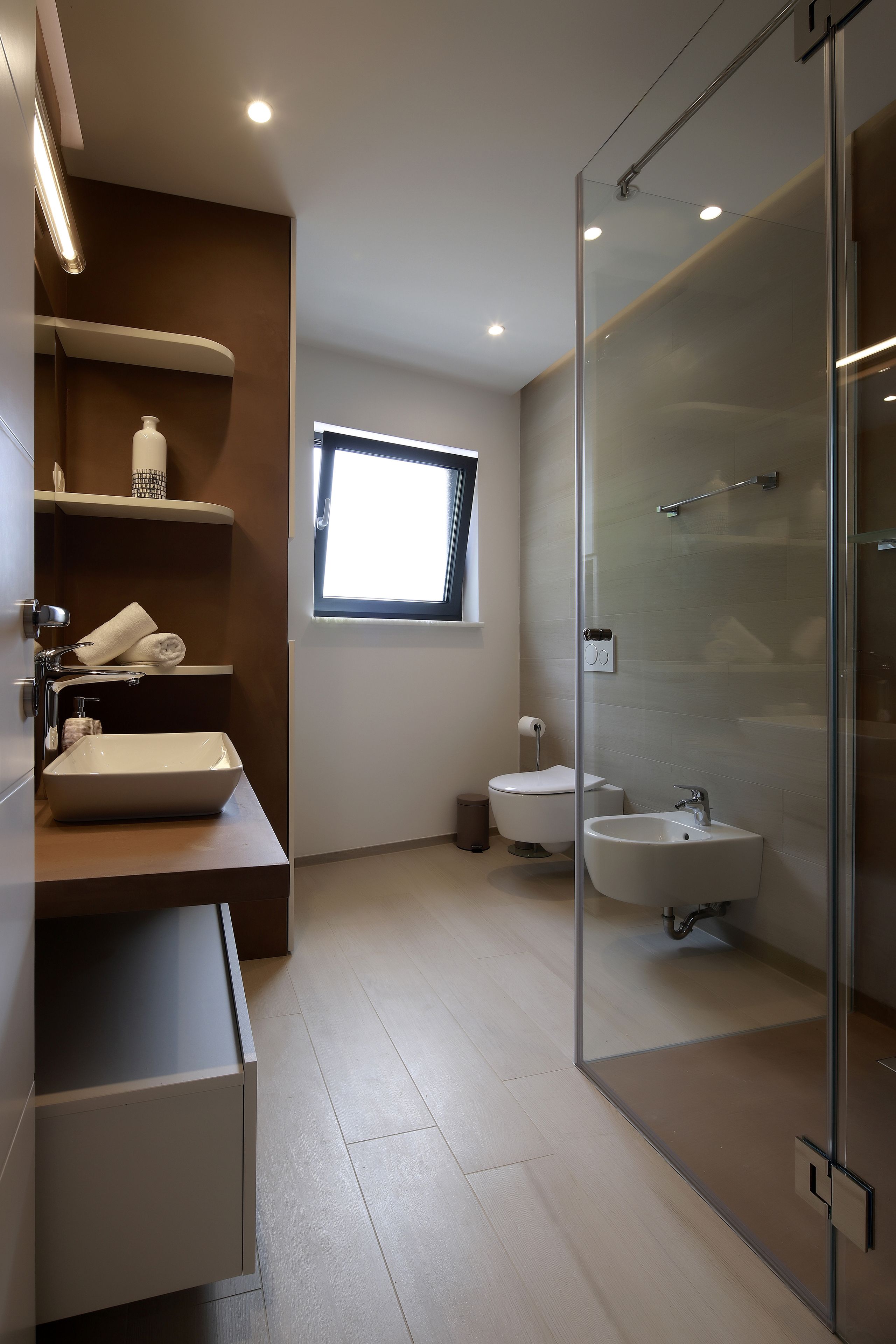 A modern bathroom with a glass shower enclosure, a toilet, and a sink.