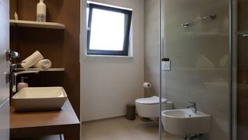 A modern bathroom with a glass shower enclosure, a toilet, and a sink.