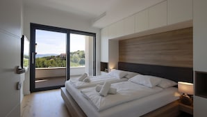 A modern bedroom with two beds, a large sliding glass door leading to a balcony, and a minimalist design. - Modena Maris Apartments (Opatija)