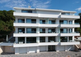 A multi-story modern building with balconies, large windows, and a flat roof.