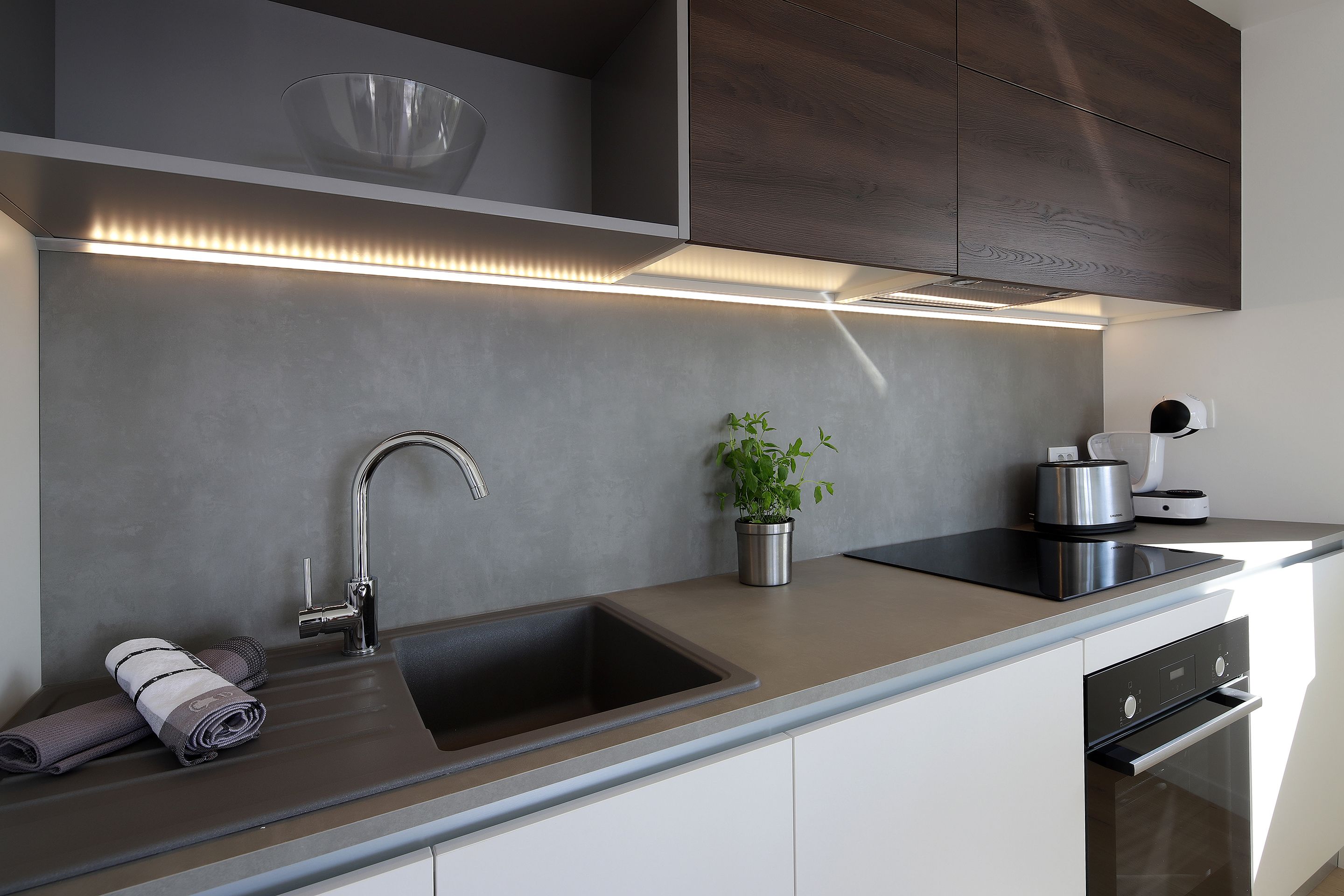 Een moderne keuken met een ingebouwd spoelreservoir, een roestvrijstalen kraan en een strak aanrecht.