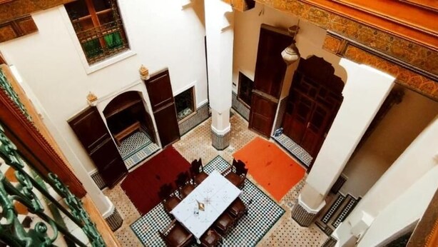 Une cour avec une table et des chaises, une cheminée et une balustrade décorative.