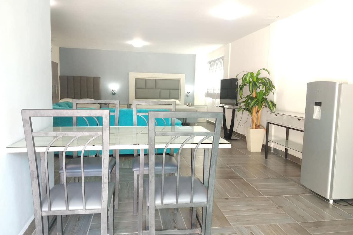 Una sala de estar moderna con comedor, un conjunto de sofá, televisor y refrigerador.