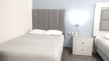 Une chambre d’hôtel avec un lit simple, une table de chevet avec une lampe et une petite table d’appoint.