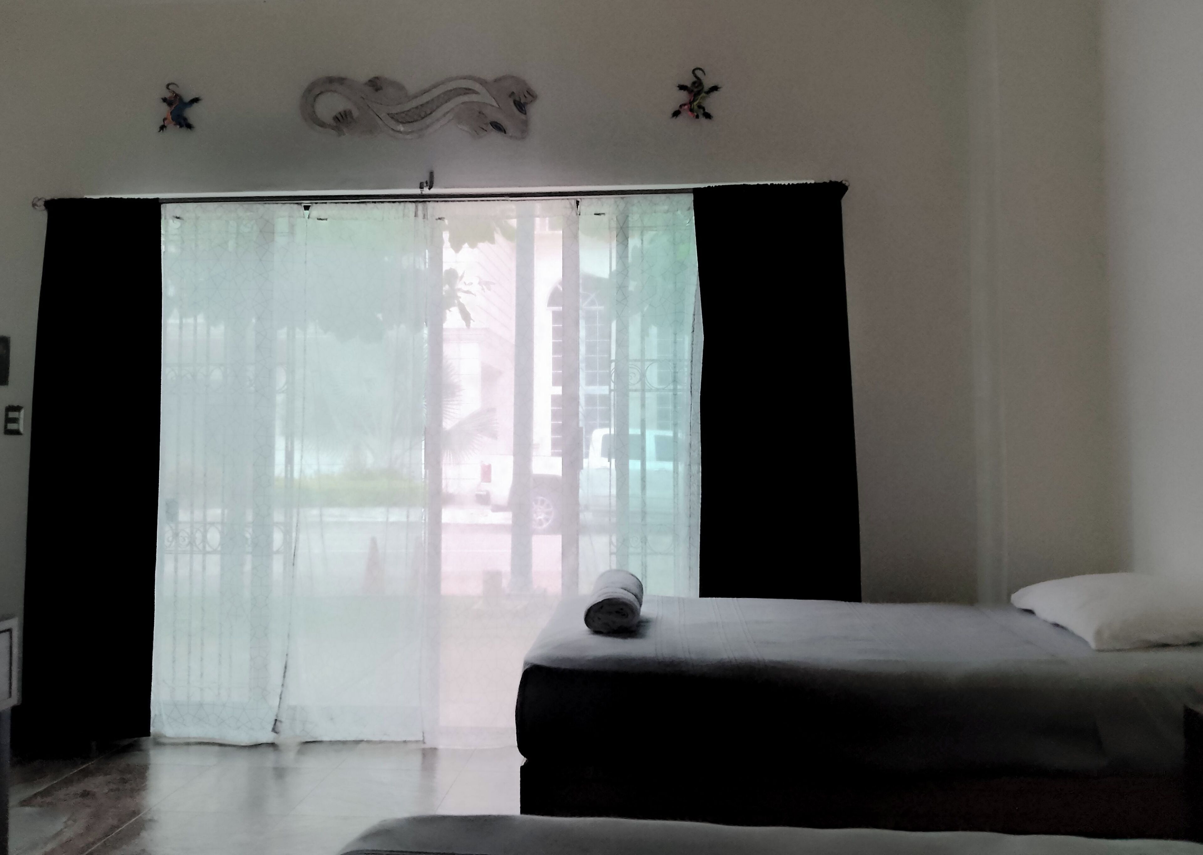 Una habitación de hotel con un amplio ventanal corredero, una cama y una mesita.