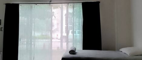 Una habitación de hotel con un amplio ventanal corredero, una cama y una mesita.