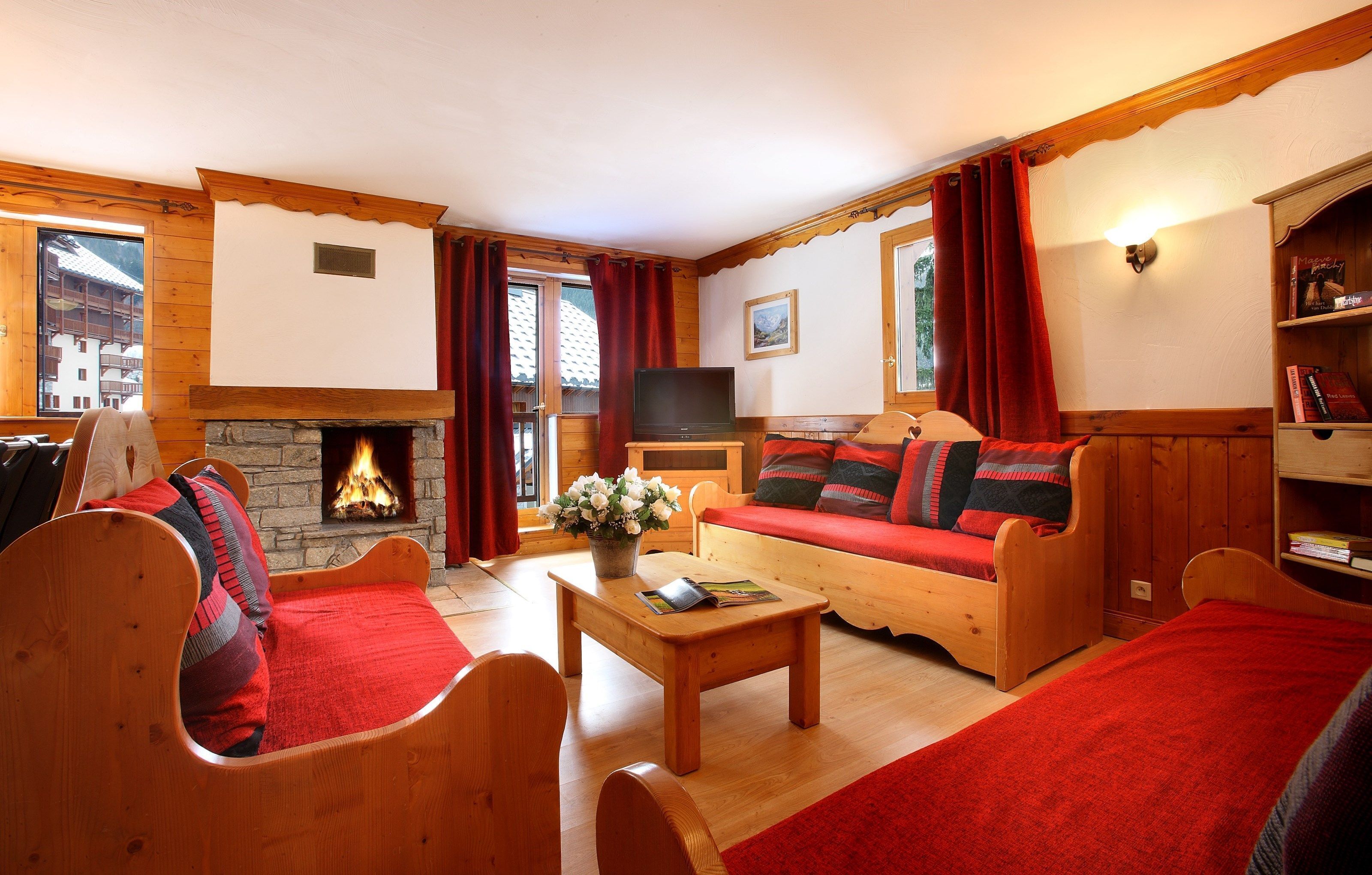 A cozy living room with a fireplace, wooden furniture, and a television.