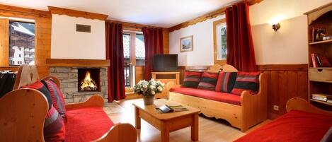 A cozy living room with a fireplace, wooden furniture, and a television.