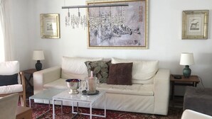 A living room with a white sofa, a glass coffee table, a red patterned rug, and a large framed artwork on the wall. - Cannes, Palm Beach, Penthouse 50 meters from the Beach (Cannes)