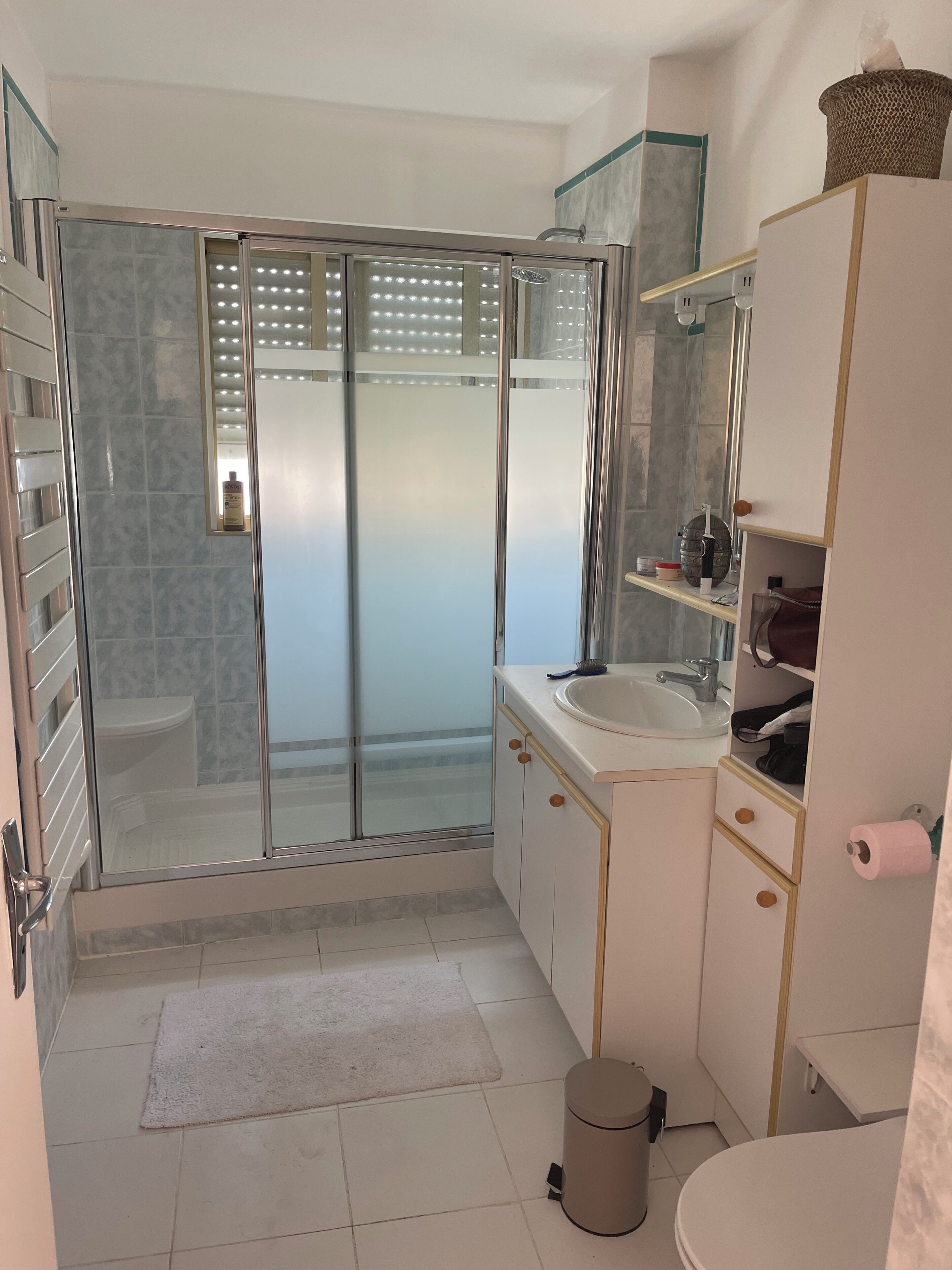 Un baño moderno con cabina de ducha de vidrio, un lavamanos con espejo y un inodoro.