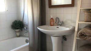 A bathroom with a bathtub, a sink, a mirror, a potted plant, and a shelf with towels. - Cannes, Palm Beach, Penthouse 50 meters from the Beach (Cannes)