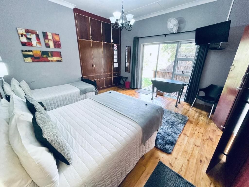 Quarto com duas camas, guarda-roupa, televisão e vista para o exterior.