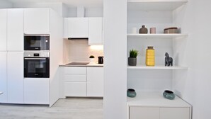 A modern kitchen with white cabinetry, a built-in oven, and a countertop with a sink.