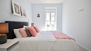 A bedroom with a bed, bedside tables, and a window with a view.
