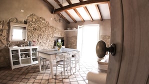 Une cuisine rustique avec un mur en pierre, un plafond en bois et un sol carrelé.