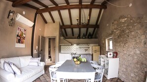 Une cuisine compacte avec une table à manger, des chaises blanches et un mur en pierre.