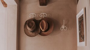 Une pièce d’angle avec un mur en pierre rustique, une poutre en bois au plafond et une petite table ronde sur laquelle est posé un vase de fleurs.