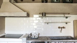 Une cuisine avec des carreaux de céramique blancs disposés en motif métro, un évier en acier inoxydable et un four encastré.