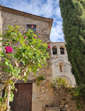 A stone building with a wooden door, a bell tower, and a large tree. - House in Rural Costa Brava (Rectoria de Dosquers) (Dosquers)