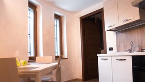 Une cuisine compacte avec un coin repas, des meubles en bois et une fenêtre qui laisse entrer la lumière naturelle.