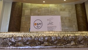 Un plafond doté d’un éclairage encastré et un mur en pierre. Une enseigne avec un logo et des coordonnées est visible.