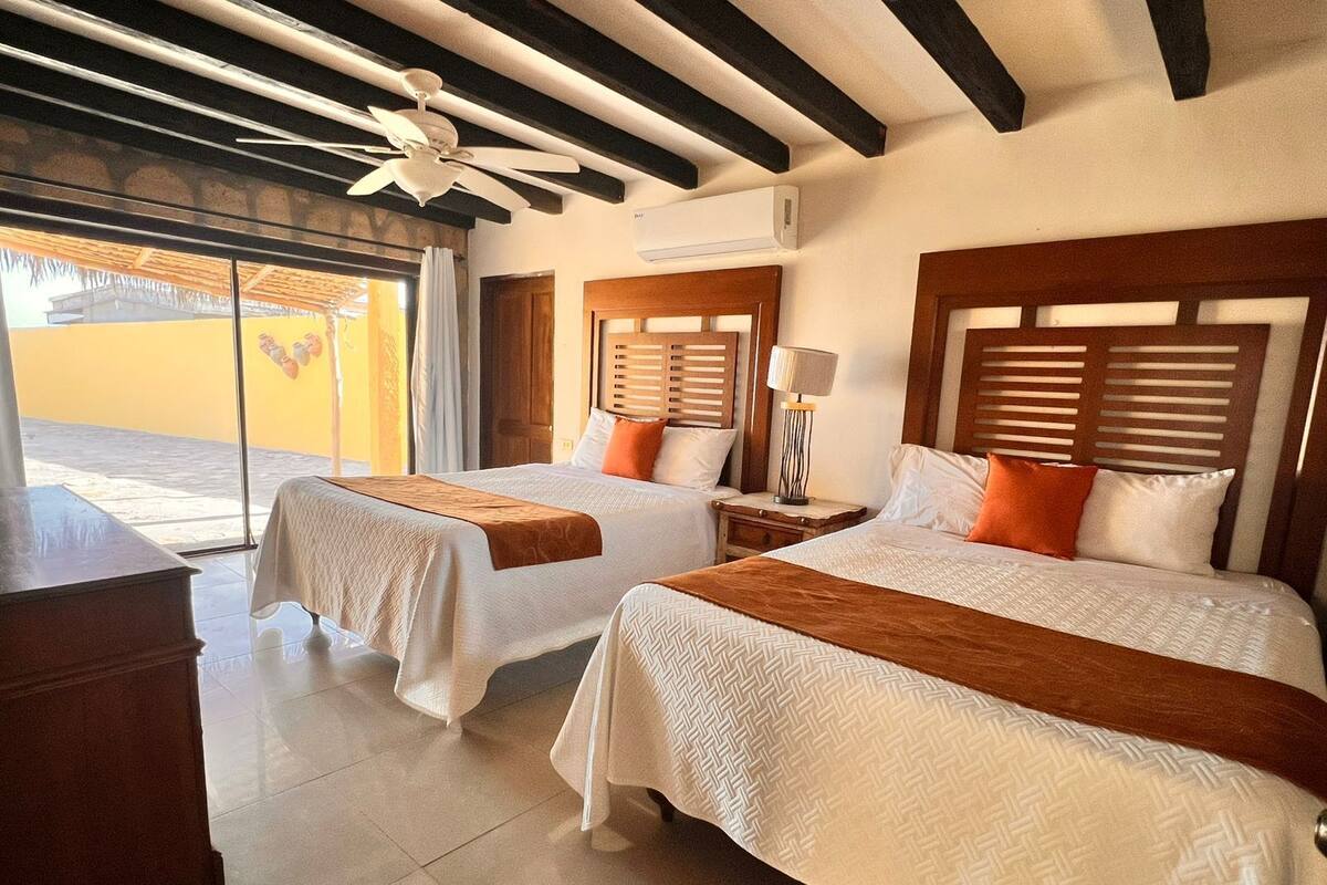 A hotel room with two beds, a ceiling fan, and a view of the outside.