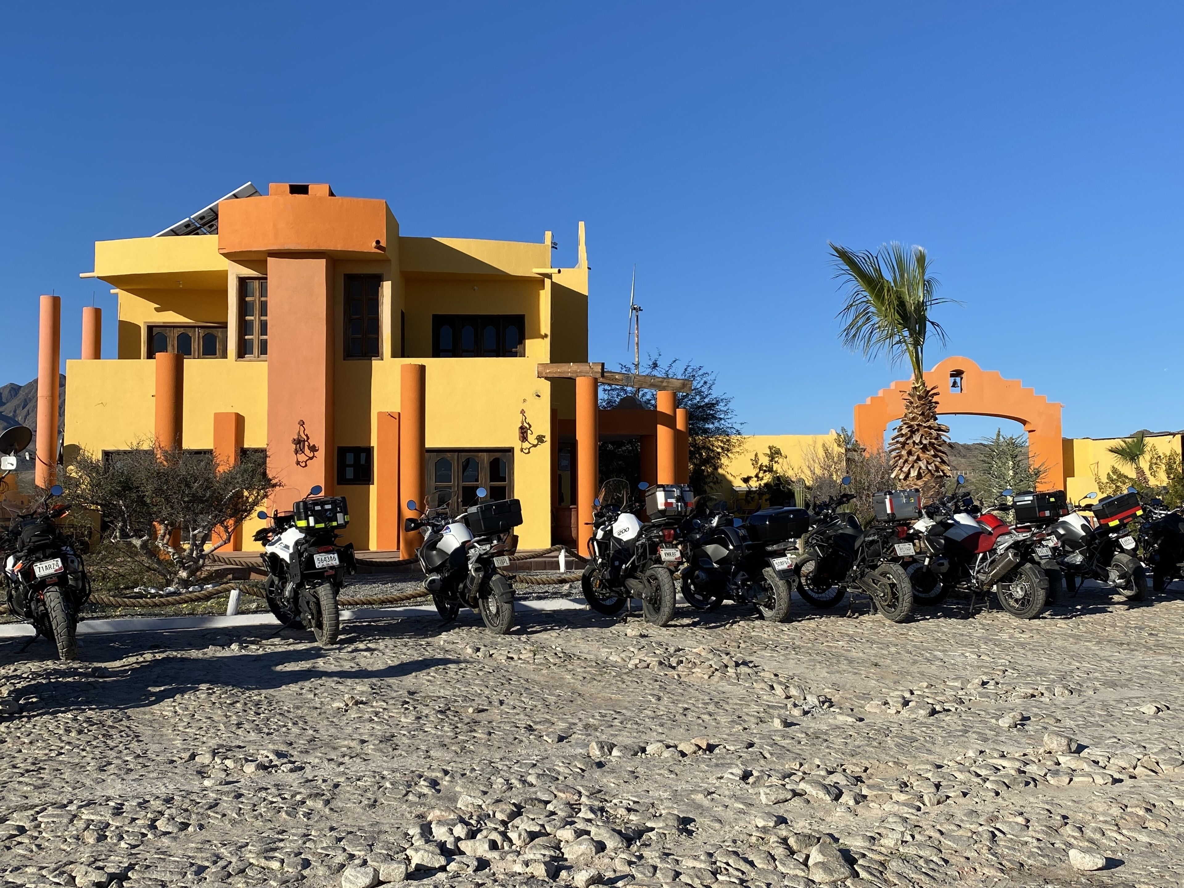 Un edificio con fachada amarilla y un gran arco, rodeado de motocicletas estacionadas.