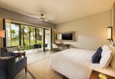 A modern hotel room with a large bed, a desk, a chair, and a TV.