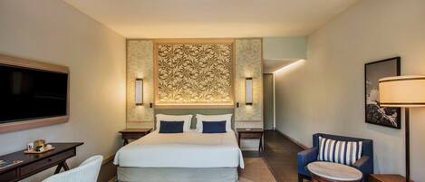 Una habitación de hotel con cama, escritorio, silla, televisión y ventilador de techo.