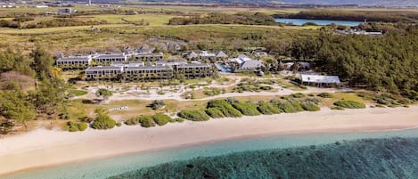 An aerial view of a resort with multiple buildings, a beach, and clear turquoise waters.