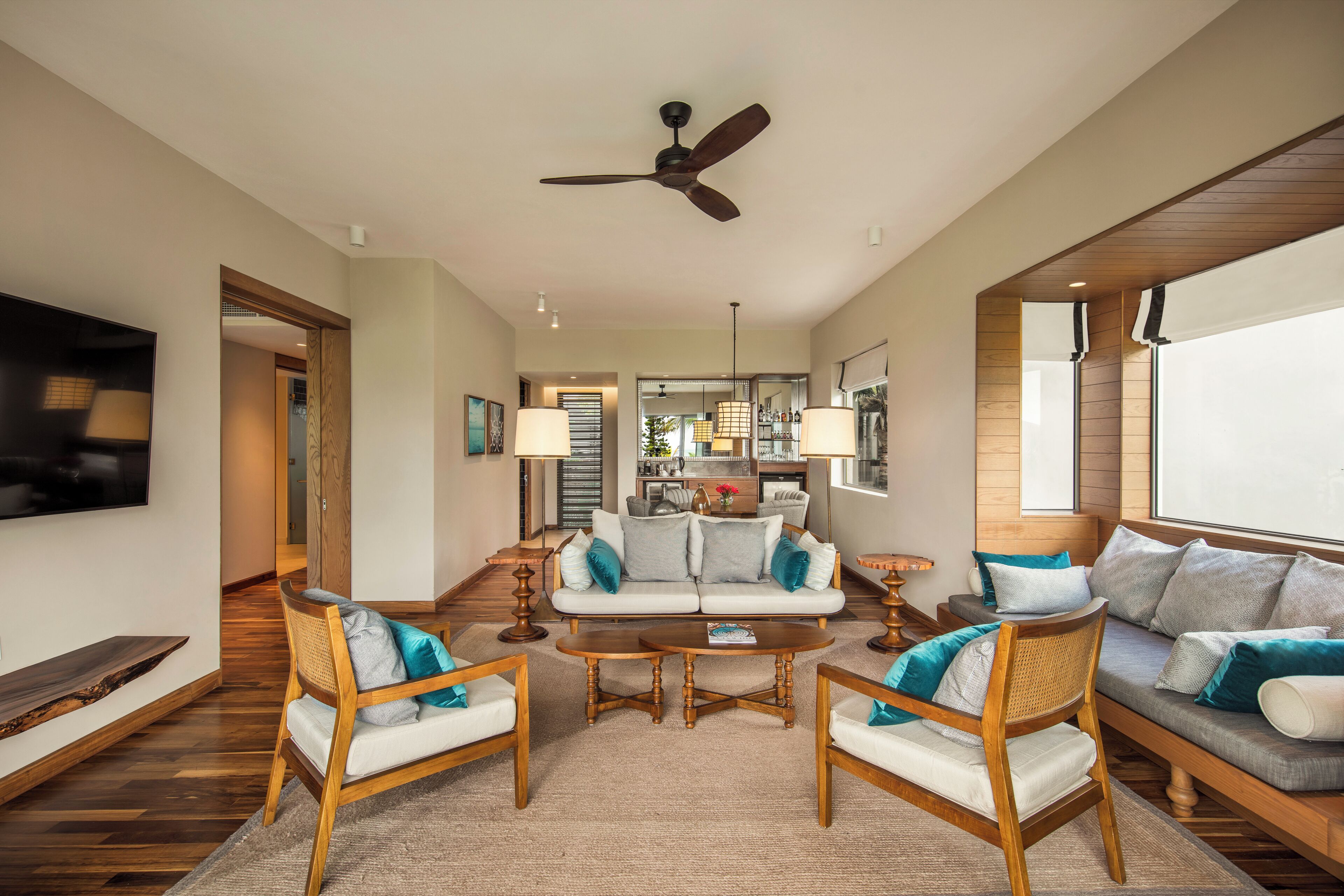 A spacious living room with a ceiling fan, a television, and a kitchen area in the background.