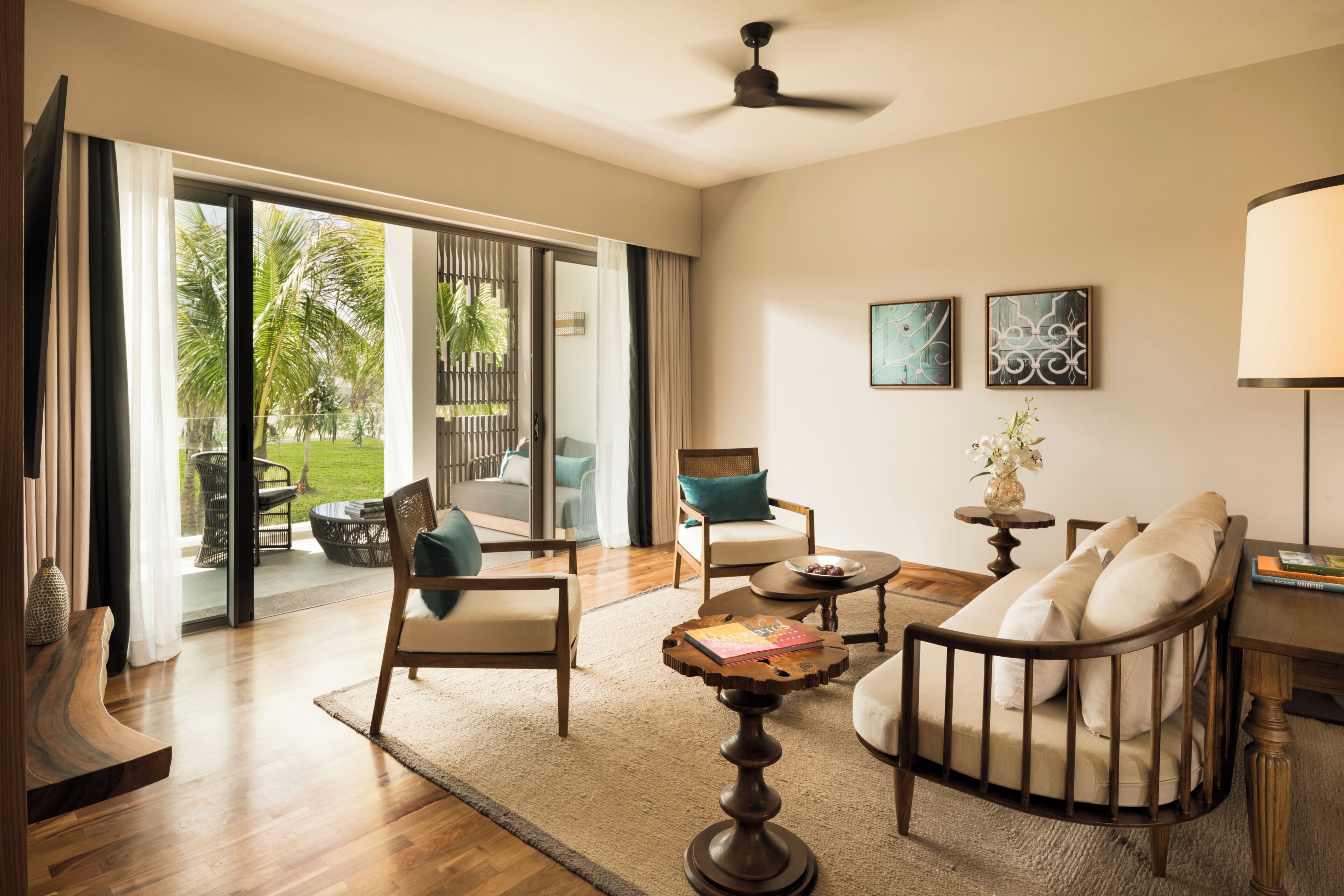 A spacious living area with a sofa, armchairs, a coffee table, and a view of a garden through large sliding doors.