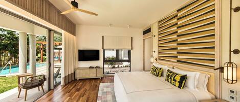 Un dormitorio moderno con una cama grande, ventilador de techo, televisor y vistas a una piscina.