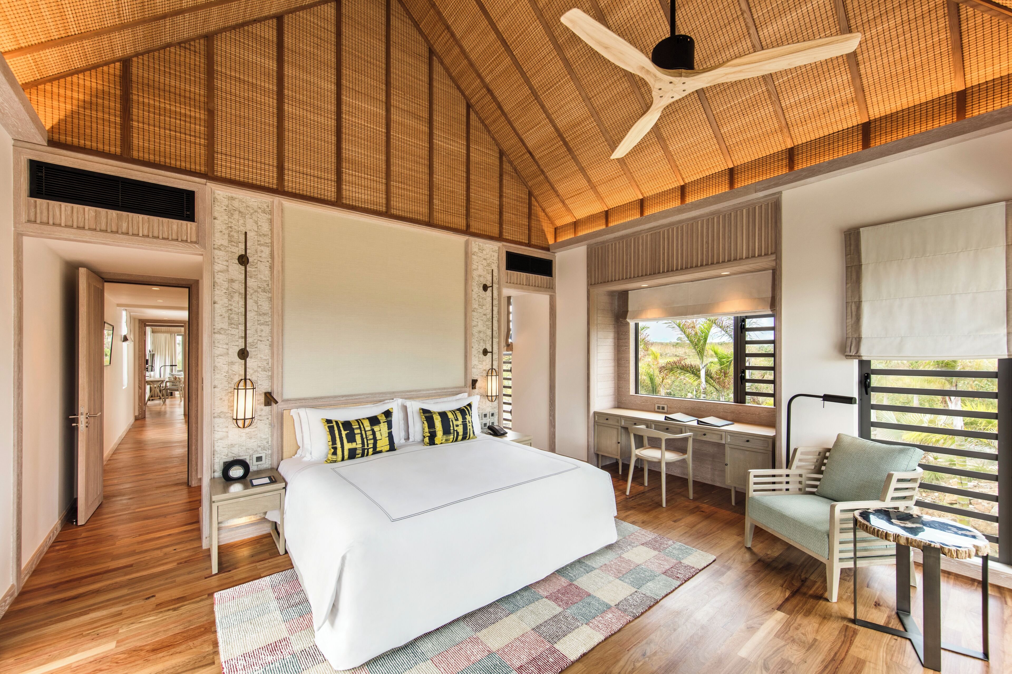 Un dormitorio amplio con una cama grande, un escritorio y vistas al exterior.
