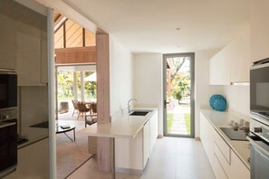 A modern kitchen with a central island, a built-in oven, and a large window.